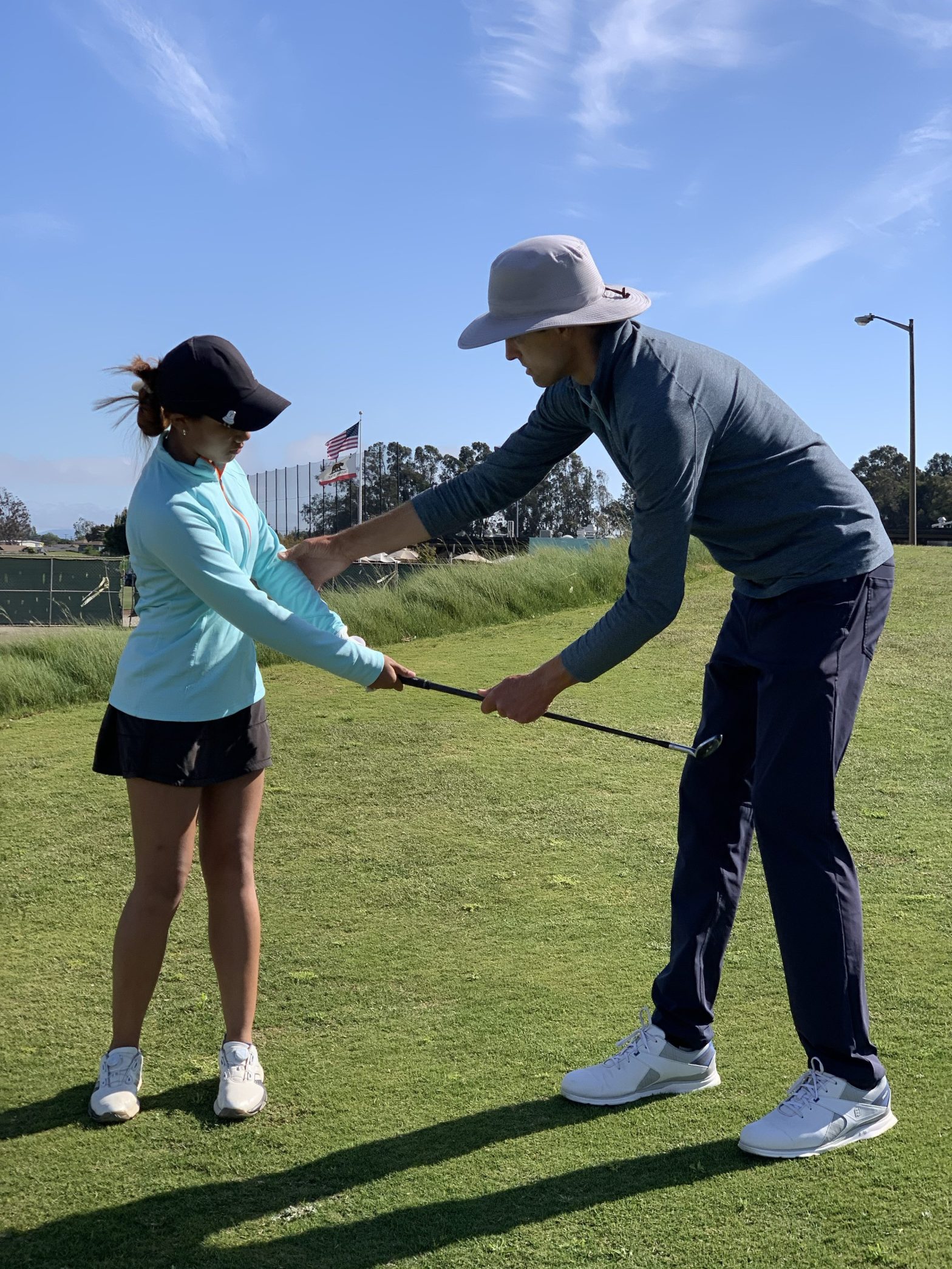Brad Marek coaching a junior golfer during an outdoor golf lesson.