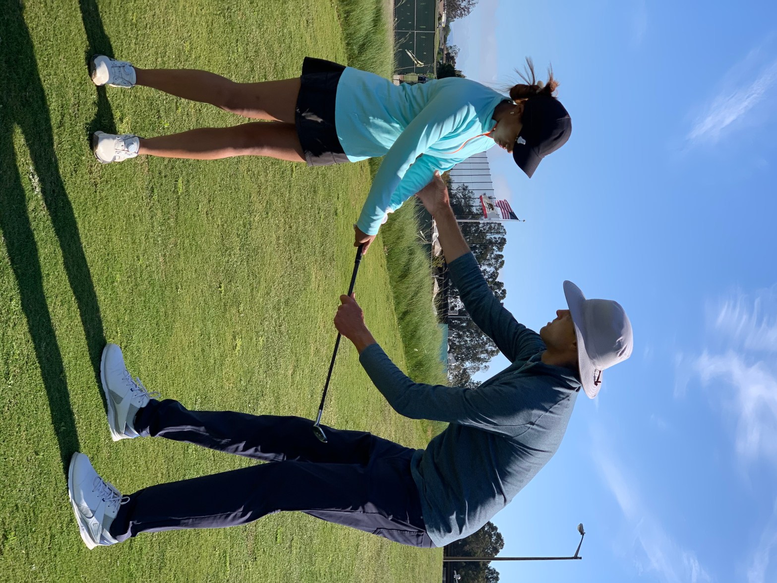 Brad Marek coaching a junior golfer during an outdoor golf lesson.